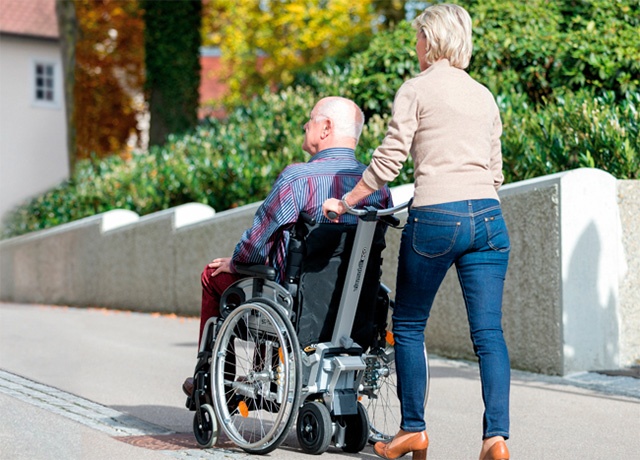 Die Brems- und Schiebehilfe Viamobil eco erleichtert die Bewegung des Rollstuhls, egal, ob es bergauf oder bergab geht